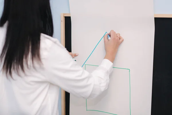 Der Lehrer schreibt an die Tafel. Weiblich zeichnet ein Haus. Vorschule — Stockfoto