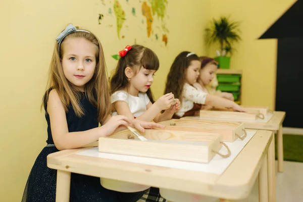 Děti ve třídě kreslí pískem. Děti používají střapec k rawingu. Školka — Stock fotografie