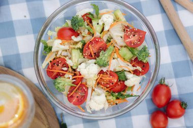 Mavi kareli peçetede taze vejetaryen salatasının en üst görüntüsü. Dışarıda vejetaryen yemeği konsepti. Üst görünüm