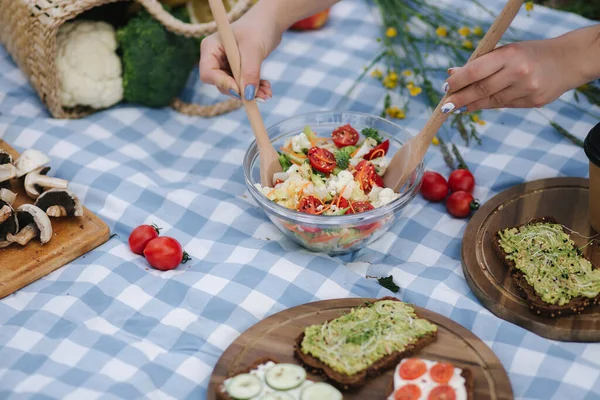外面野餐时,女人把蔬菜沙拉混合在一起.巴巴多斯的食物概念 — 图库照片