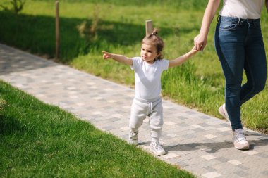 Sevimli küçük kız annesiyle evde vakit geçiriyor. Anne ve kızı arka bahçede yürüyor.