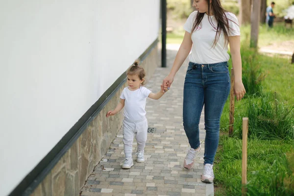 Roztomilá holčička tráví čas s mámou v domě. Matka a dcera procházka po dvorku — Stock fotografie