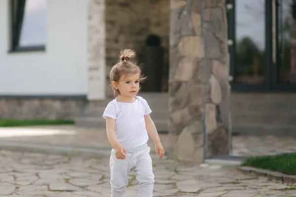 Schattig klein meisje loopt in de buurt van het huis. Mooi kind brengt tijd door voor het huis — Stockfoto