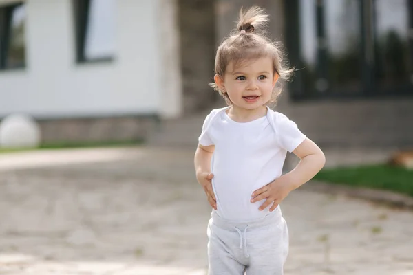 Una adorable niñita camina cerca de la casa. Hermoso niño pasar tiempo en frente de la casa — Foto de Stock