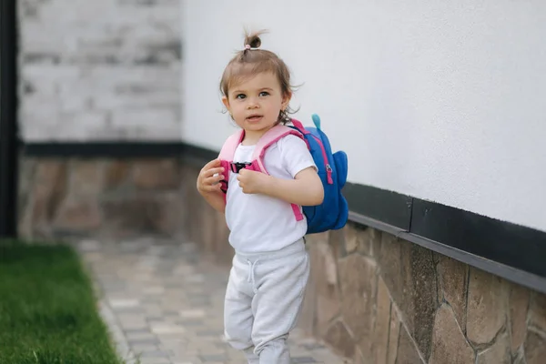 Carino bambina con zaino a piedi vicino alla casa — Foto Stock