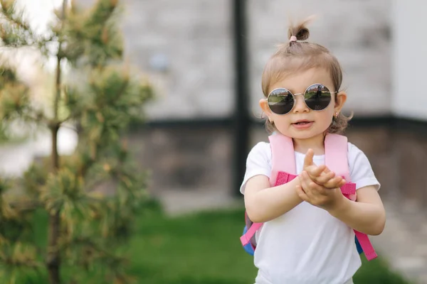 Ritratto di Happy litle girl passeggiata in gront di casa con zaino. Carino un anno e mezzo ragazza in occhiali da sole — Foto Stock