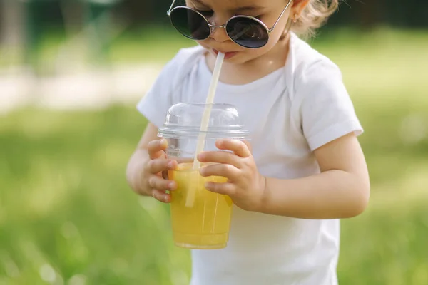 Közelkép aranyos kislány fehér testruha és napszemüveg inni limonádé szabadban — Stock Fotó