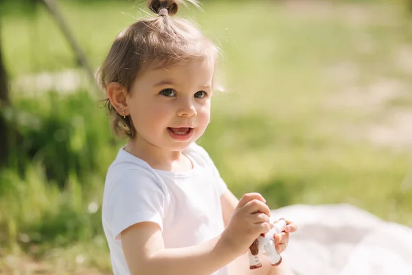 Il bambino felice si siede all'aperto sul tappeto e gioca con gli animali giocattolo. Adorabile bambina in body bianco — Foto Stock