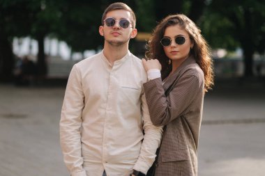 Şehirde yürüyen mutlu bir çift. Kıvırcık saçlı çekici bir genç kadın ve şehrin merkezinde yakışıklı bir genç adam. Dışarıda güneş gözlüklü insanlar gülümsüyordu.