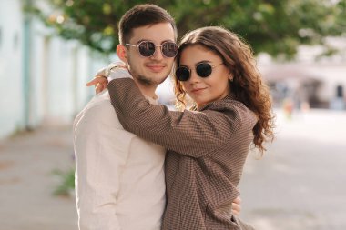 Şehirde yürüyen mutlu bir çift. Kıvırcık saçlı çekici bir genç kadın ve şehrin merkezinde yakışıklı bir genç adam. Dışarıda güneş gözlüklü insanlar gülümsüyordu.