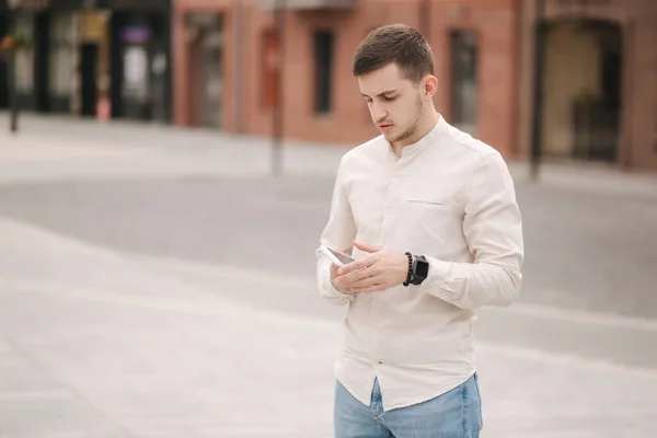 Un joven guapo usando su teléfono en el centro de la ciudad. Hombre llamando a su novia — Foto de Stock