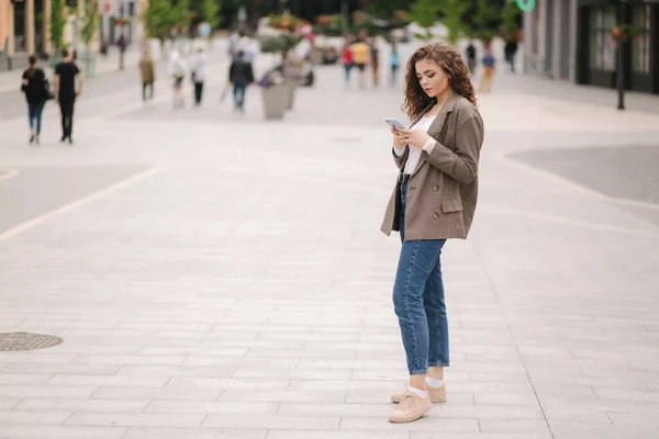 Attraktive junge Frau benutzt Telefon in der Stadt. Glückliche schöne Frau schreibt Massage am Telefon, online — Stockfoto
