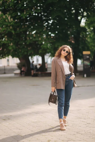 Porträt einer attraktiven Frau mit lockigem Haar und Sonnenbrille im Freien. Glückliche junge Frau spaziert durch die Stadt — Stockfoto