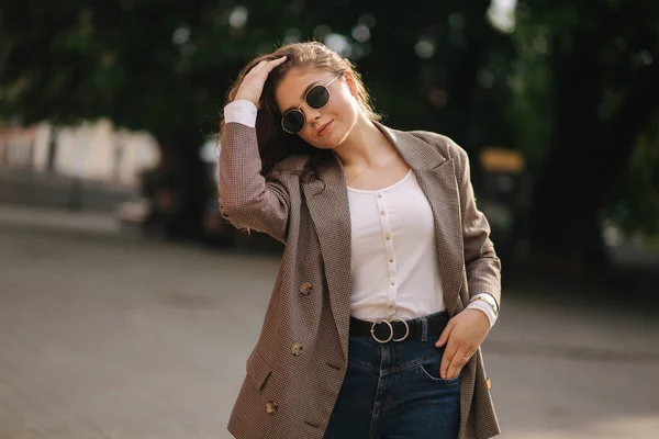 Retrato de mujer atractiva con pelo rizado en gafas de sol al aire libre. Feliz joven mujer caminando en la ciudad —  Fotos de Stock