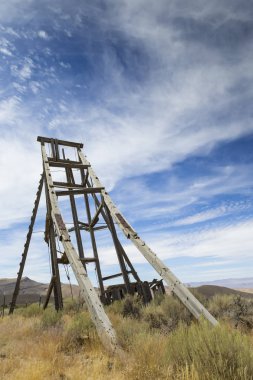 Eski baş çerçeve bulutlar ile mavi gökyüzü altında Nevada Çölü'nde madencilik.