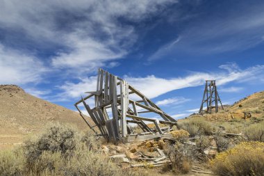 Eski baş çerçeve bulutlar ile mavi gökyüzü altında Nevada Çölü'nde madencilik.