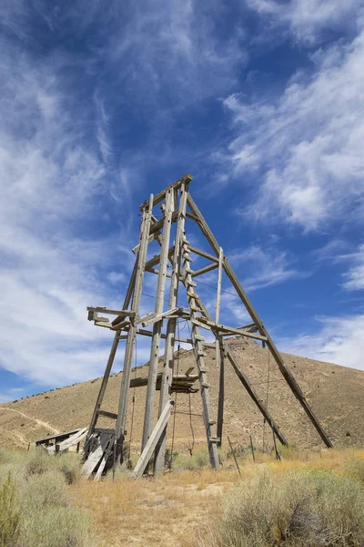 Antiguo marco de la cabeza minera en el desierto de Nevada bajo el cielo azul con nubes . — Foto de Stock