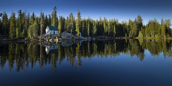 Mosquito Lake, California. Sierra lake with mirror reflection of forest, blue sky, trees and cabins. — Stock Photo, Image