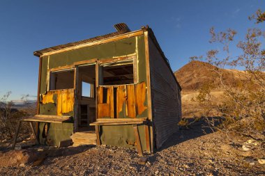 Eski terk edilmiş kulübesi Rhyolite hayalet kasaba erken sabah ışık ile Nevada çölünde açık mavi gökyüzü.