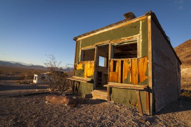 Eski terk edilmiş kulübesi Rhyolite hayalet kasaba erken sabah ışık ile Nevada çölünde açık mavi gökyüzü.