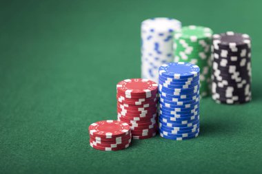 Poker fişleri Yeşil Keçe tablo üzerinde yığılmış. Sığ derinlik-in tarla açık yığın odaklı.