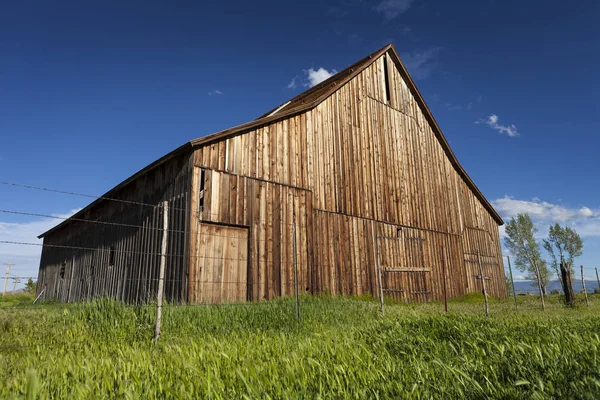 Ancienne grange vintage sur ranch avec ciel bleu et herbe verte . — Photo