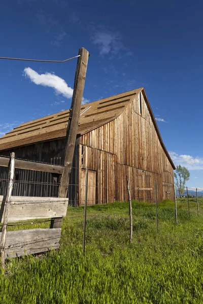 Ancienne grange vintage sur ranch avec ciel bleu et herbe verte . — Photo