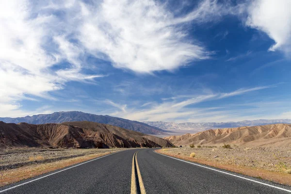 Death Valley desert roadway with blue sky.