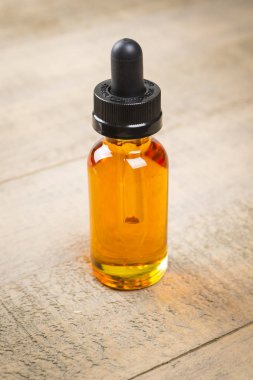 Vaping e-çiğ meyve suyu şişeleri ahşap arka plan üzerinde. E-suyu çocuk geçirmez kapaklı şişe.