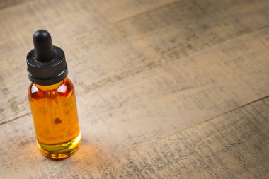 Vaping e-çiğ meyve suyu şişeleri ahşap arka plan üzerinde. E-suyu çocuk geçirmez kapaklı şişe.