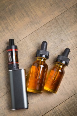 Vaping mod e-cig tank atomizer ve suyu şişe üzerinde tahta arka plan ile