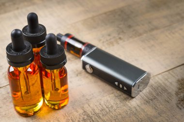 Vaping mod e-cig tank atomizer ve suyu şişe üzerinde tahta arka plan ile