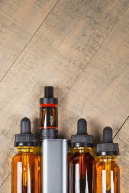 Vaping mod e-cig tank atomizer ve suyu şişe üzerinde tahta arka plan ile