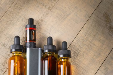 Vaping mod e-cig tank atomizer ve suyu şişe üzerinde tahta arka plan ile