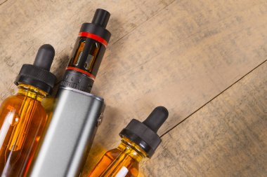 Vaping mod e-cig tank atomizer ve suyu şişe üzerinde tahta arka plan ile