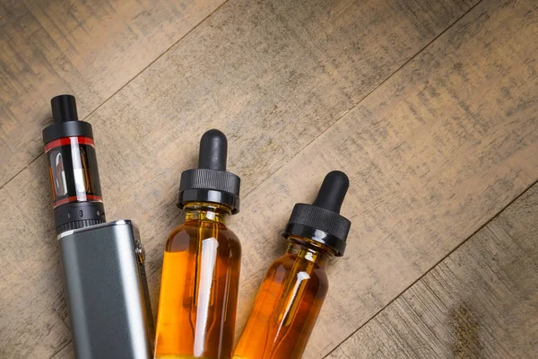 Vaping mod e-cig tank atomizer ve suyu şişe üzerinde tahta arka plan ile