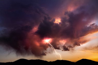 Lighting bolt striking from colorful clouds at sunset in the Nevada desert clipart