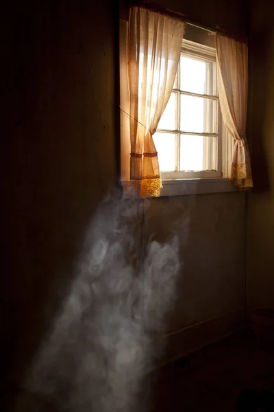 Årgang behandlet gammelt forlatt soverom med røyk opplyst av et åpent vindu med gardiner – stockfoto
