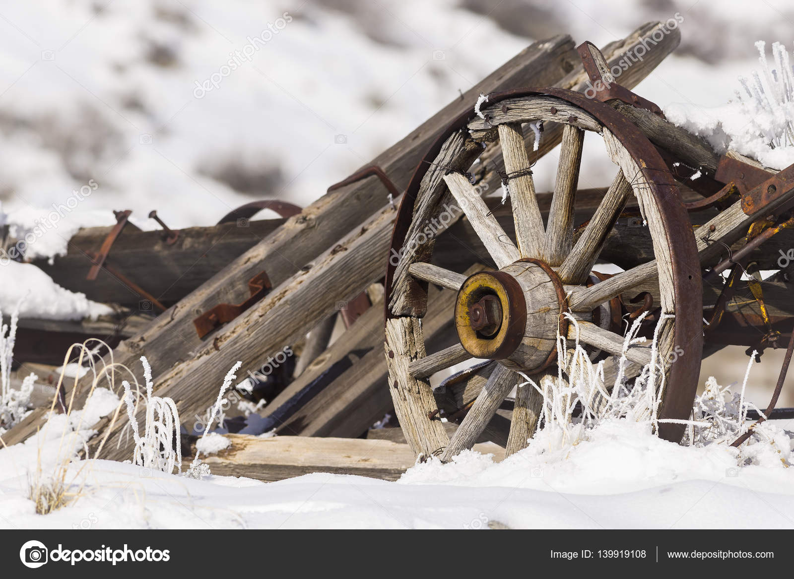 Old broken wagon with wheel in snow and frost with winter background