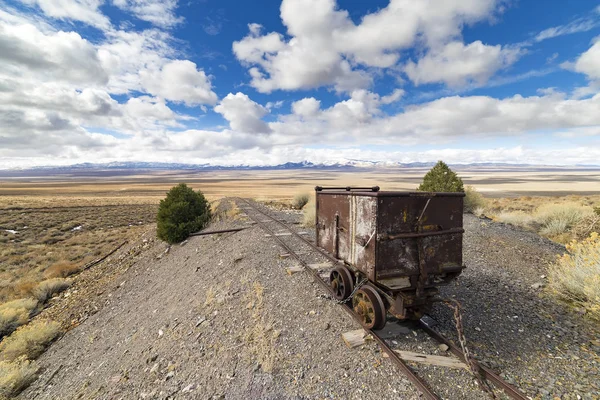 Stary koszyk ore górnictwa na torach pod piękne błękitne niebo z chmurami na pustyni Nevada w Berlinie Ghost Town. — Zdjęcie stockowe