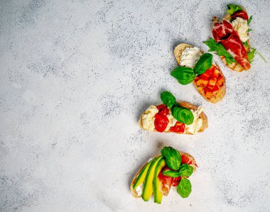 Hafif arka planda farklı lezzetli bruschettalar, düz bir zemin. Üst görünüm