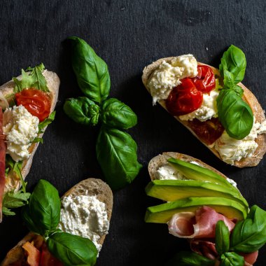 Esmer arka planda farklı lezzetli bruschettalar, düz yatış. Üst görünüm