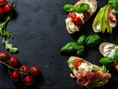 Esmer arka planda farklı lezzetli bruschettalar, düz yatış. Üst görünüm