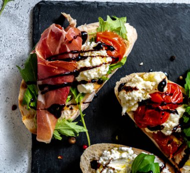 Esmer arka planda farklı lezzetli bruschettalar, düz yatış. Üst görünüm