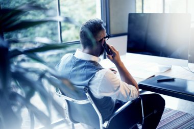 Sakallı işadamı cep telefonu arama ortağı Meeting.Person dijital Tablet masaüstü tablo işyerinde kullanan Modern Loft başlangıç Computer.Creative genç adam çalışan beyaz gömlek yelek giyiyor.