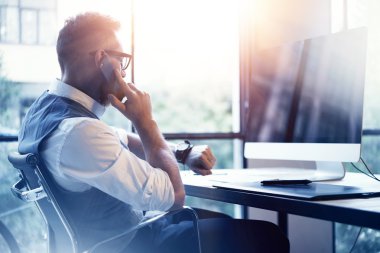 Sakallı işadamı cep telefonu kullanan Modern Loft başlangıç Computer.Creative genç adam çalışan beyaz gömlek yelek giyen arama ortağı Meeting.Gentleman izle Workplace.Blurred fişekleri arayan adam.
