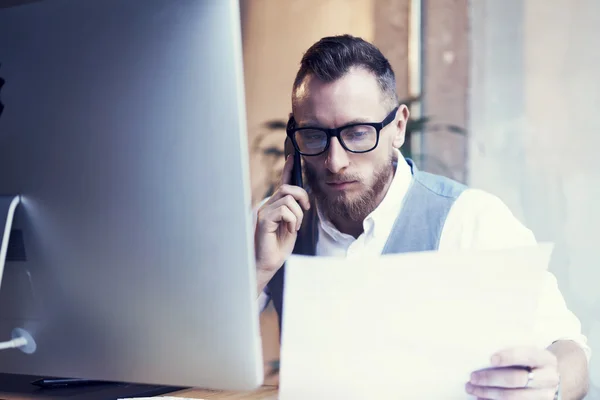 Nahaufnahme bärtige Geschäftsmann arbeiten Arbeitsplatz report.man mit Smartphone-Anruf Treffen partner.young guy tragen weiße Hemd Weste Arbeit Start-up desktop.people große Geschäftsentscheidungen Büro. — Stockfoto