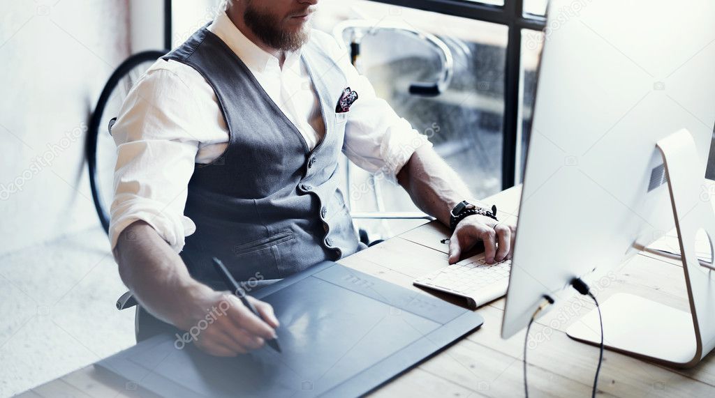 Closeup Bearded Graphic Designer Working Drawing Digital Tablet Desktop Computer Wood Table.Stylish Young Man Wearing Glasses White Shirt Waistcoat Work Modern Loft Creative Startup Project Blurred.
