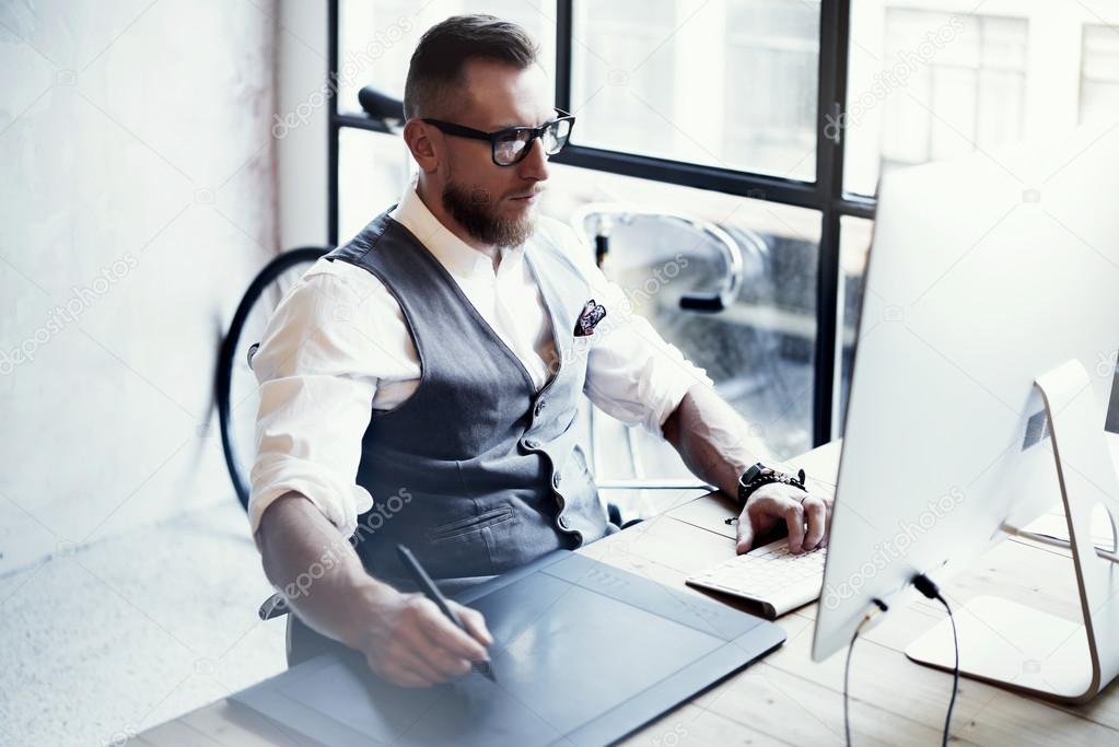 Bearded Graphic Designer Working Digital Tablet Drawing Desktop Computer Wood Table.Stylish Young Man Wearing Glasses White Shirt Waistcoat Work Modern Loft Creative Startup Project Blurred Horizontal