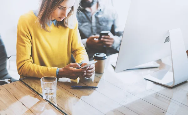 Coworking process in modern office e.Woman looking to her mobile phone and sitting at a wooden table.Man typing on his smartphone.Horizontal photo, blurred background . — стоковое фото